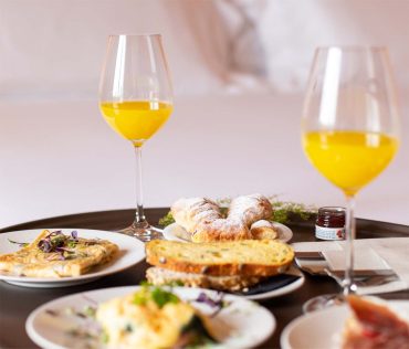 Petit déjeuner avec viennoiseries, pain et jus de fruit servi en chambre d’hôtes