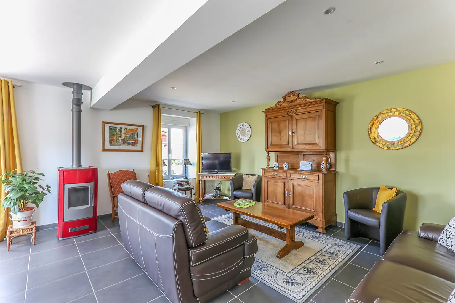 Salon chaleureux de gîte avec poêle à bois, canapé en cuir et espace détente lumineux à la campagne